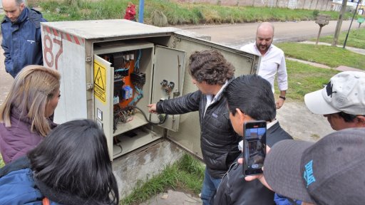 Utility staff and partners inspect an electrical control cabinet during a field visit, discussing ways to improve system reliability and reduce service interruptions.