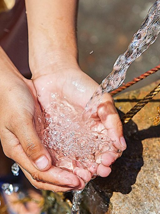 Hands under a water pipe